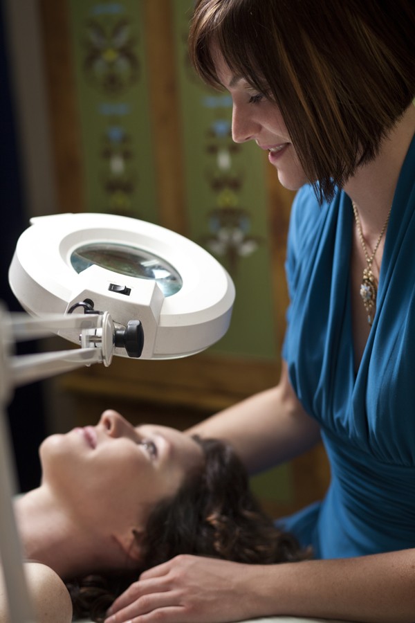 A woman is getting her face cleaned by an optometrist.