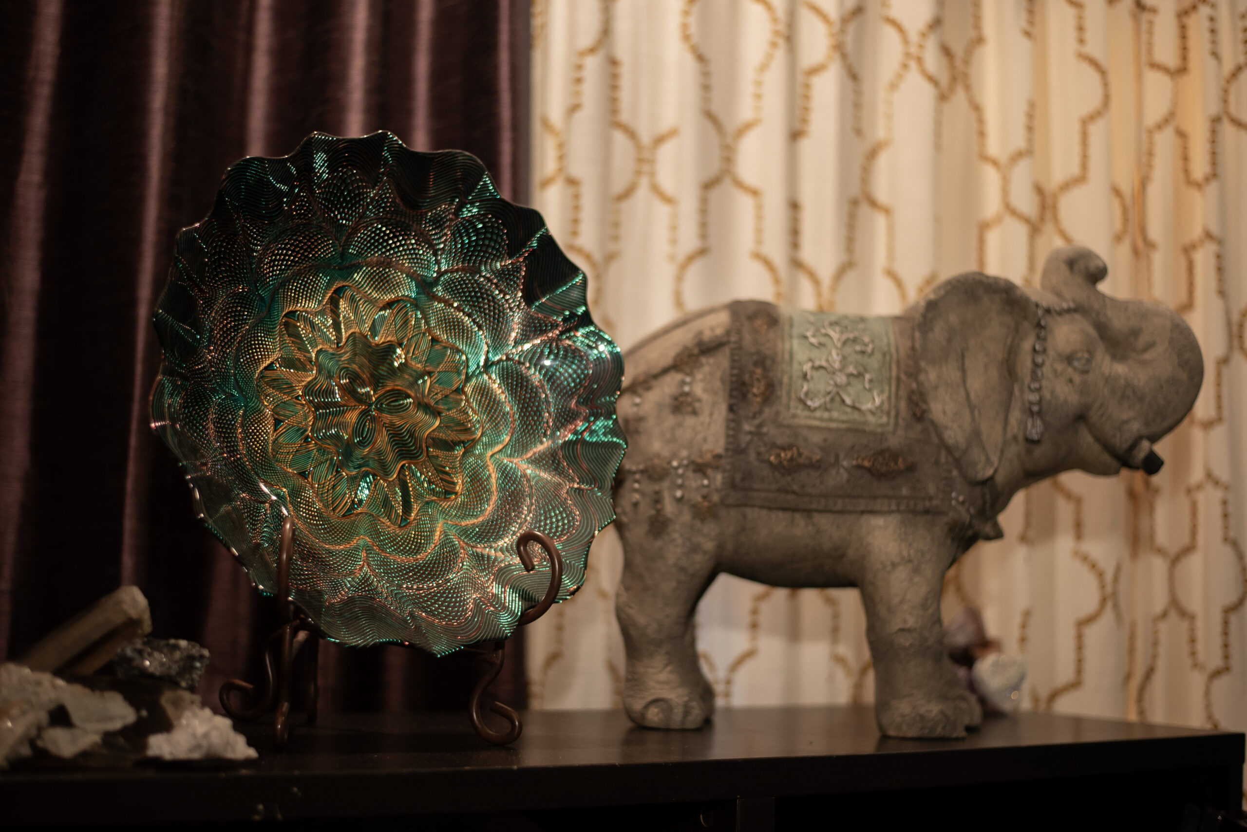 A table with an elephant statue and a decorative glass bowl.